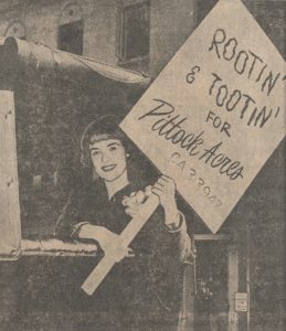 Rose Festival princess waves a booster sign to show her support for Pittock Mansion at the antique car parade fundraiser. Published in the Portland Reporter March 25, 1964