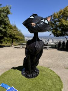 Black painted statue of Coraline's Cat from LAIKA's, Coraline, at the Pittock Mansion viewpoint as part of the Coraline's Curious Cat Trail campaign to celebrate the movie's 15 year anniversary and to fundraise for doernbecher children's hospital in Portland, Oregon.